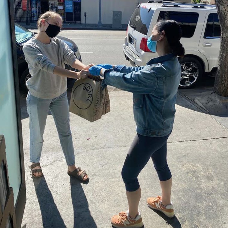 A Sqirl staffer hands a free meal-for-two to another hospitality professional.