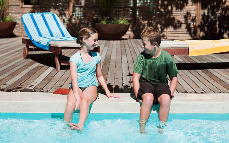 Boy and girl sitting on edge of pool talking