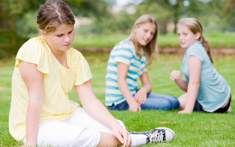 Two girls in background bullying girl in yellow shirt