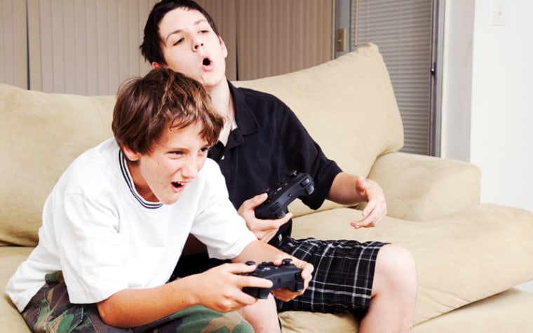 Two boys sitting on couch playing videogames