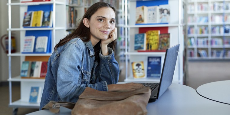 Confident young female student sitting at desk