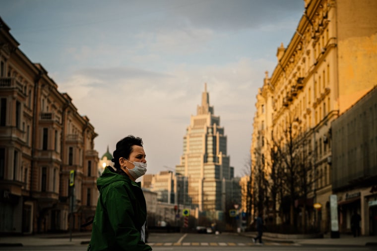 Image: A woman wearing a face mask walks in a deserted street in central Moscow
