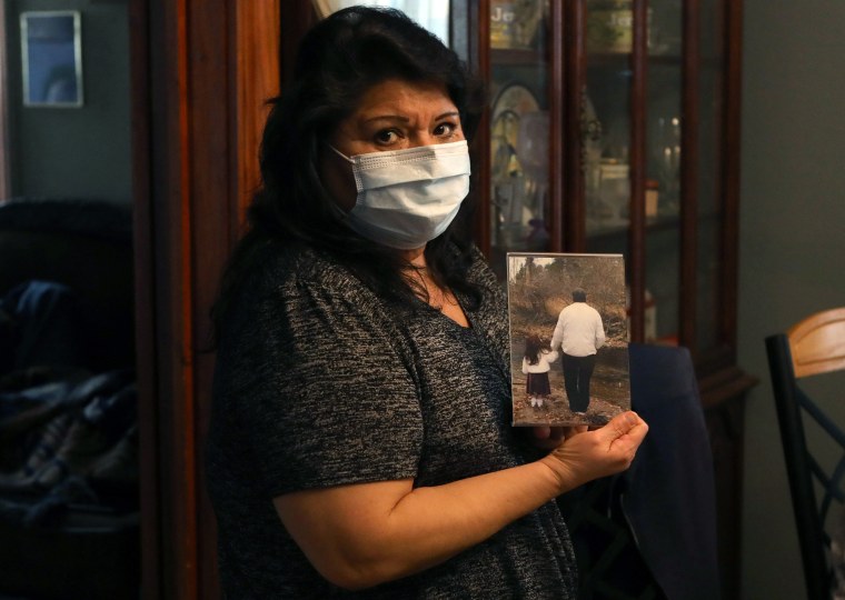 Image: Estela Hernandez, a daughter of longtime JBS USA meat packing plant employee Saul Sanchez, holds a photo of him in Greeley