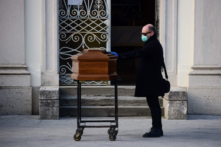 Image: A man touches his mother's coffin