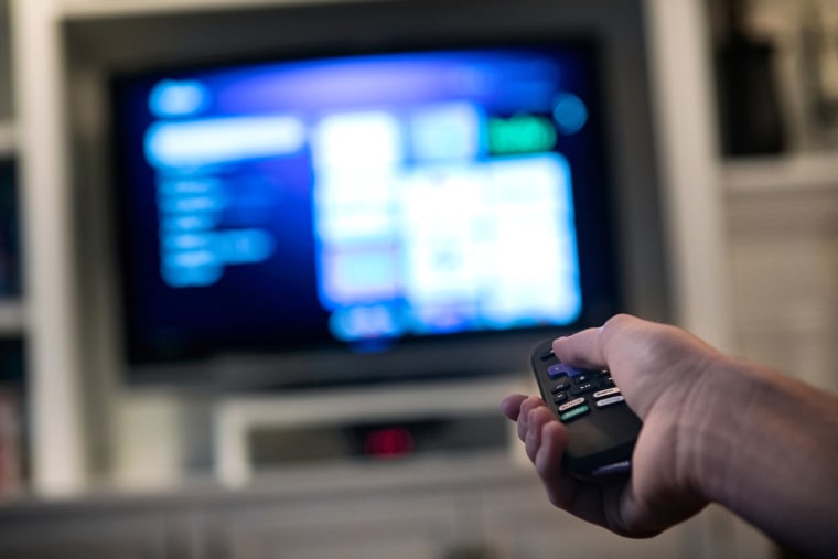 Image: A consumer in a home using a modern smart television to stream various content.