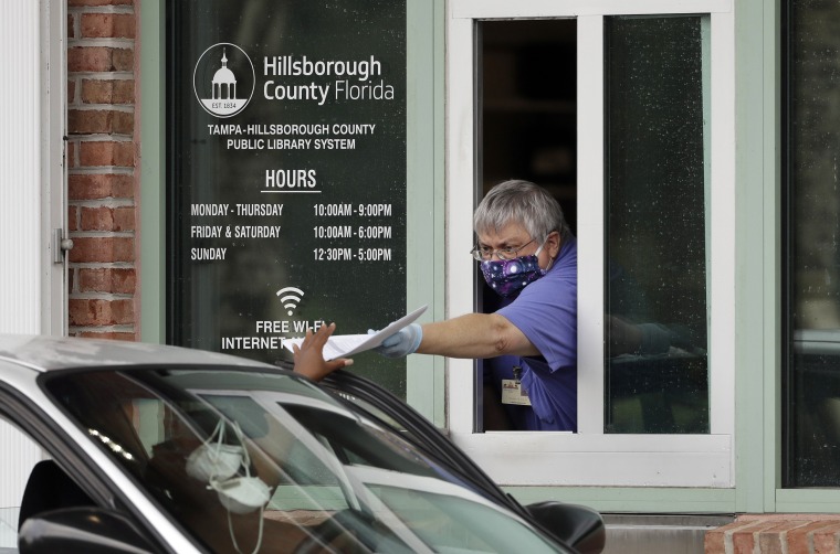 Image: A Hillsborough County Library Service employee hands out unemployment paperwork in Tampa, Fla.,