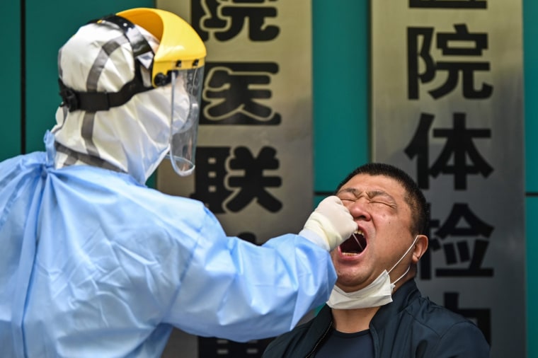 Image: A man being tested for the COVID-19 novel coronavirus reacts as a medical worker takes a swab sample in Wuhan in China's central Hubei province