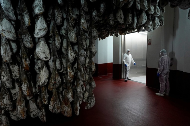 Image: Alberto Andres Gonzalez and Jose Gomez speaks in a ham cellar at Joselito ham factory during the coronavirus disease (COVID-19) outbreak in Guijuelo, Spain