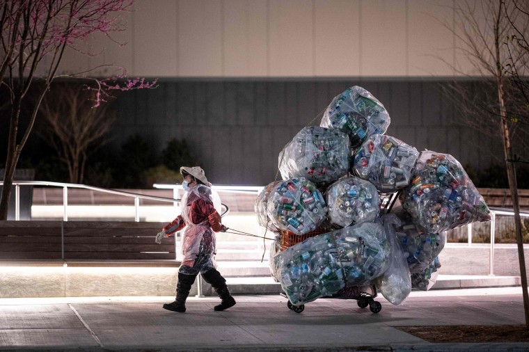 Image: A woman wearing a face mask and a plastic bag pulls a cart loaded with bags of recyclables through the streets of Lower Manhattan during the outbreak of the novel coronavirus (which causes COVID-19) on April 16, 2020 in New York City.