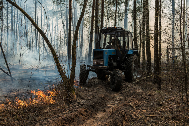 Image: A tractor operator makes a trench in the forest to prevent fire from spreading in the forest near Krasiatychi, Kyiv region, Ukraine