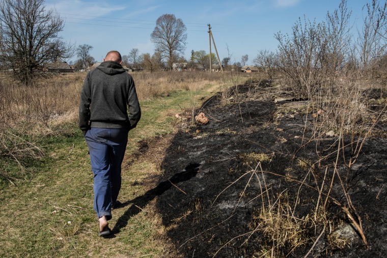 Image: Andriy Budych, 27, who didn't want his face to be shown, walks near the place where he recently set garbage and grass on fire, which according to police then spread to the Chornobyl Exlusion Zone, in the village of Rahivka, Kyiv region, Ukraine