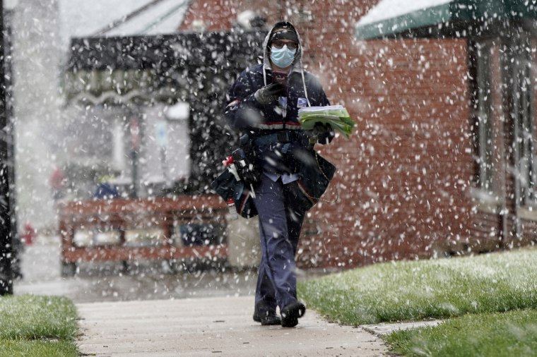 A mail carrier wears a face mask during a spring snow storm in Lincoln, Neb., on April 16, 2020.