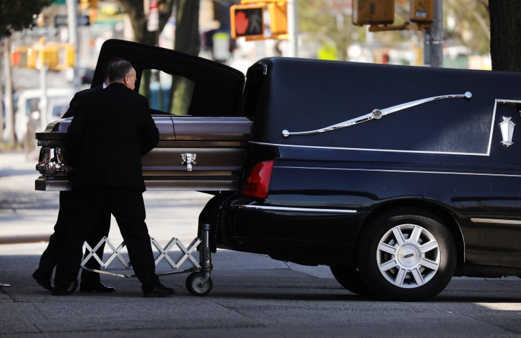 Image: A casket is placed into a hearse outside a funeral home in Brooklyn, N.Y.