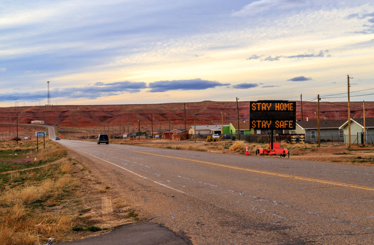 A sign in Many Farms, Ariz., tells Navajos to stay home as the tribal nation experiences an increasing number of coronavirus cases.