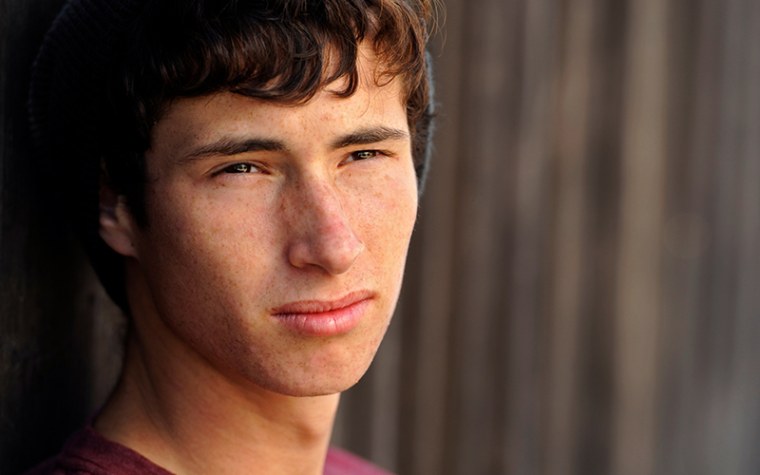 College aged boy wearing beanie staring off into a distance unhappy