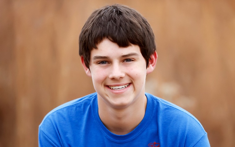 College aged man in dark blue shit smiling at camera