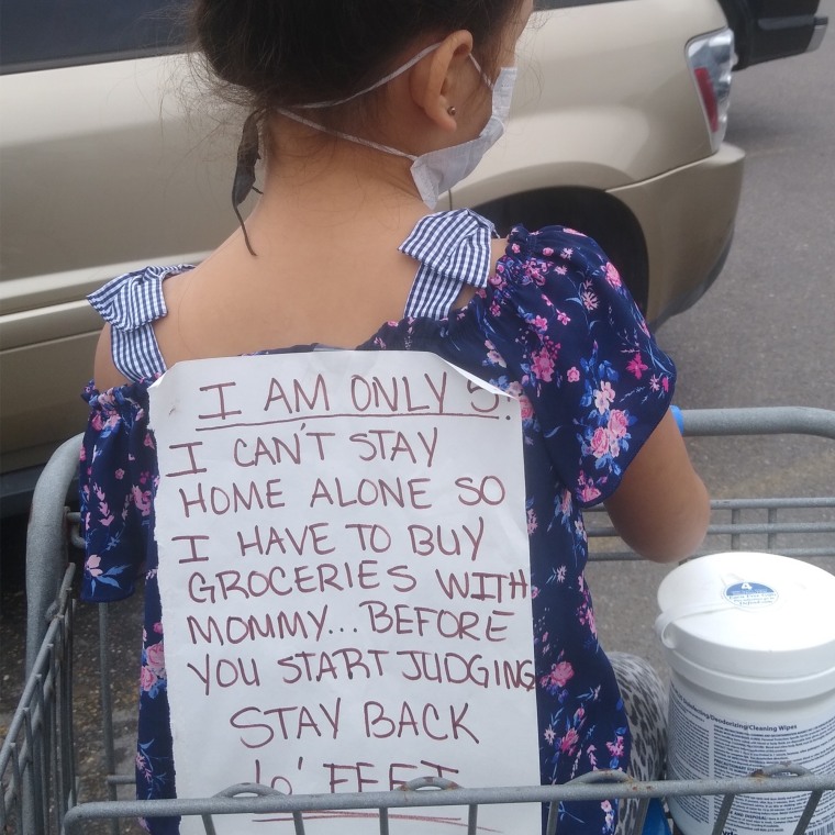 MaryAnn Resendez taped a sign on her daughter's back explaining why they were both in a supermarket during a pandemic.