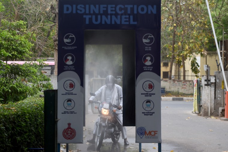 Image: A man drives through a disinfection tunnel outside the local government offices in Faridabad, India on Monday as a preventive measure against coronavirus.
