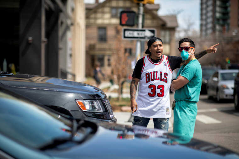 Image: A protester against stay-at-home orders yells near a health care worker outside of the State Capitol in Denver on April 19, 2020.