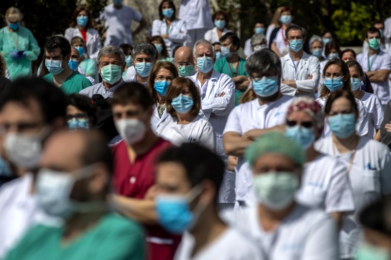 Image: Health care workers observe a moment of silence on Monday to remember Joaquin Diaz, the chief of surgery at Madrid's La Paz hospital, who died of COVID-19.