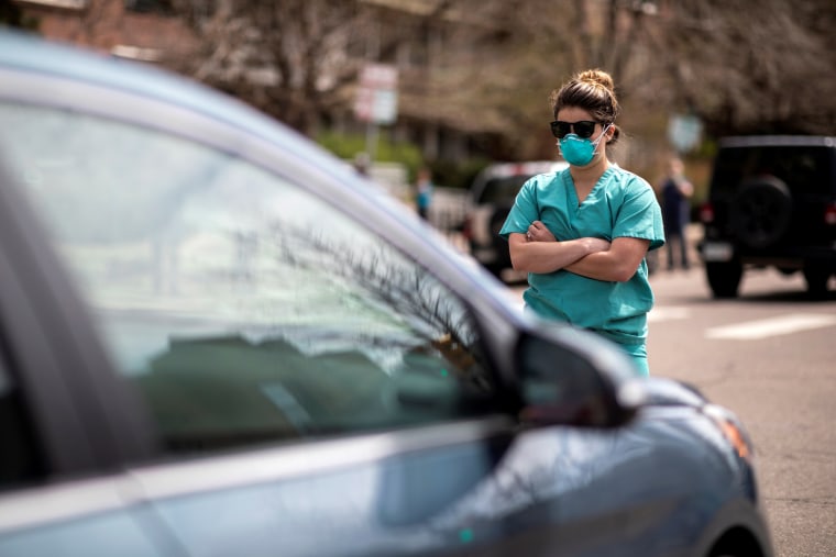 Image: Health care workers stand in the street as a counter-protest to those demanding the stay-at-home order be lifted in Denver