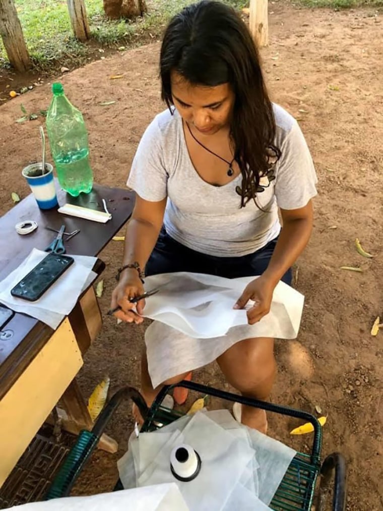 Image: A health worker makes masks in Brazil