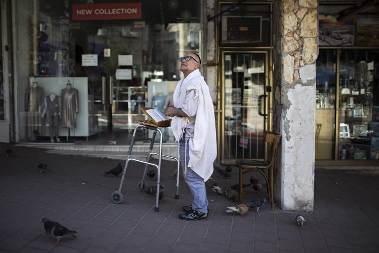 Image: A man prays next to his house in Bnei Brak last week.