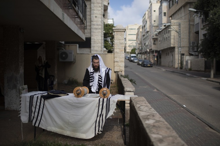 Image: An Ultra-Orthodox Jew prays a morning prayer next to his house as synagogues are closed following the government's measures to help stop the spread of the coronavirus, in Bnei Brak