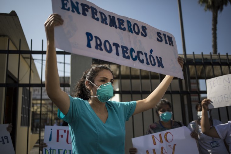 A nurse holds up a sign that reads, "Nurses without protection," to protest the lack of protective equipment for health care workers outside a hospital in Lima, Peru, on April 20, 2020.