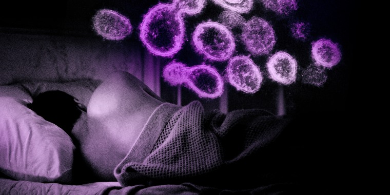 Image: A man sleeping on a bed while coronavirus hovers above in the darkness