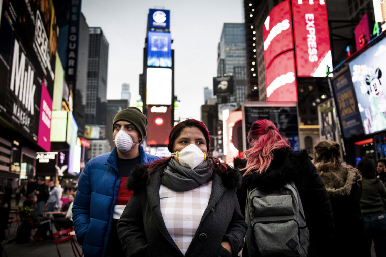 Image: Pedestrians wearing face masks walk through New York's Times Square on March 12, 2020.