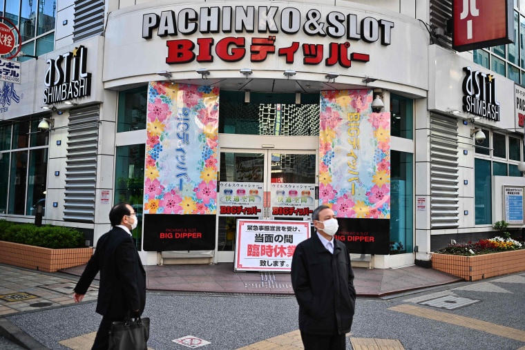 Image: A man wearing a face mask walks in front of a closed pachinko parlor in Tokyo on Friday.