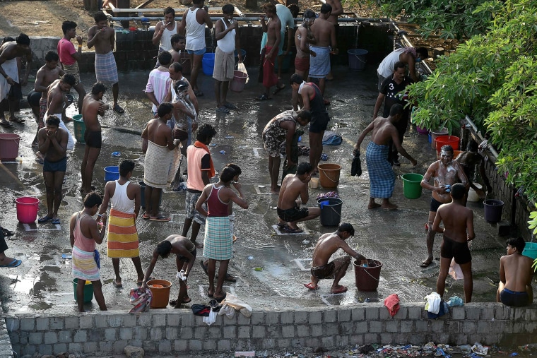 Image: Construction workers take an early morning bath in Mumbai during a nationwide lockdown on Friday.
