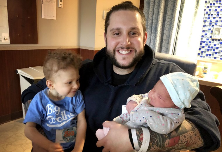 Image: Jonathan Coelho holds his son Braedyn and daughter Penelope.