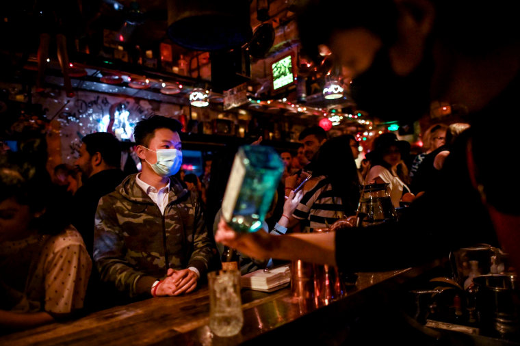 Image: A man waits at the bar while patrons dance in Shanghai on April 26, 2020.
