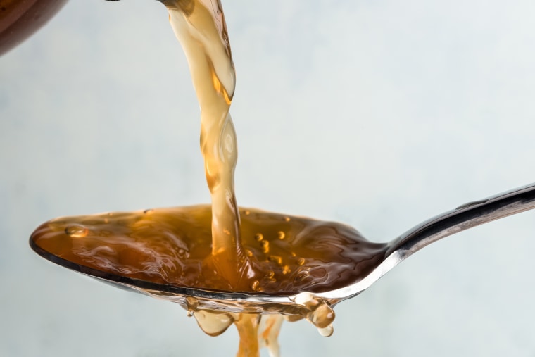 Close-Up Of Vinegar Pouring In Spoon Against White Background