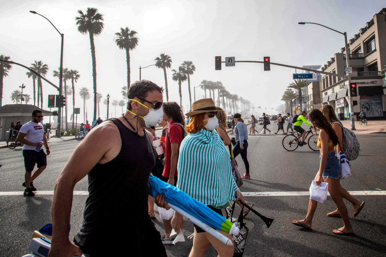 Image: Pedestrians cross the street near Huntington Beach, Calif., on April 25, 2020. Orange County beaches remain open amidst other social distancing measures to curb the spread of coronavirus.