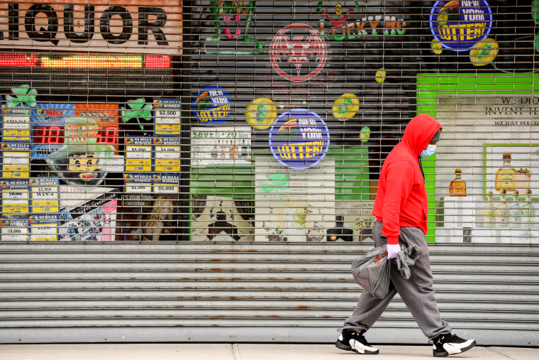 Image: A pedestrian walks past closed storefronts in Central Islip, N.Y., on March 25, 2020.