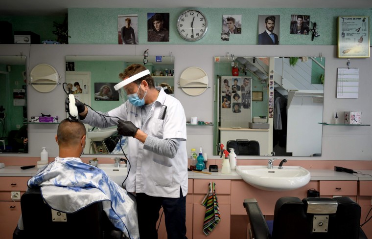 Image: A barber cuts a customers hair in Lausanne after the Swiss government eased social distancing restrictions on April 27, 2020.