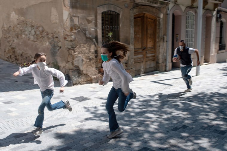 Image: Joan, 45, chases his daughters Ines, 11, and Mar, 9, as they play in the street on April 26, 2020, in Barcelona, during a national lockdown to prevent the spread of the COVID-19 disease.