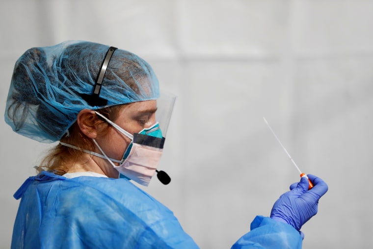 Image: Lindsey Leinbach looks at a coronavirus test swab at a facility in the Bronx, N.Y., on April 21, 2020.