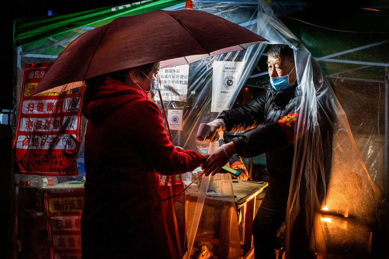 Image: A resident of a small community in China's northeastern Heilongjiang province has their temperature checked before being allowed to enter