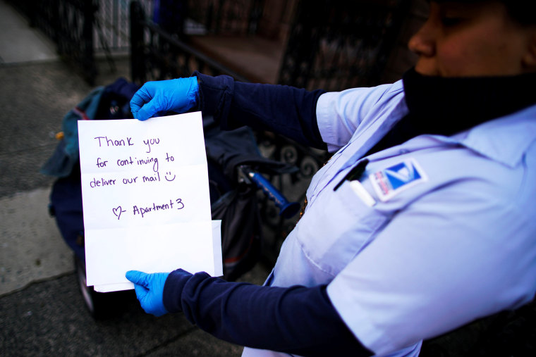 Image: A US Postal Service worker shows a note of appreciation while delivering mail in Hoboken, N.J., on April 25, 2020.