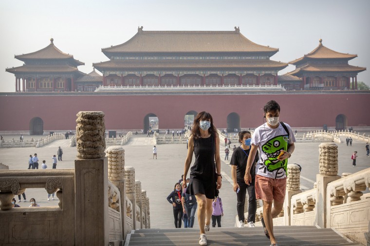 Image: Visitors wearing face masks to protect against the new coronavirus walk through the Forbidden City in Beijing