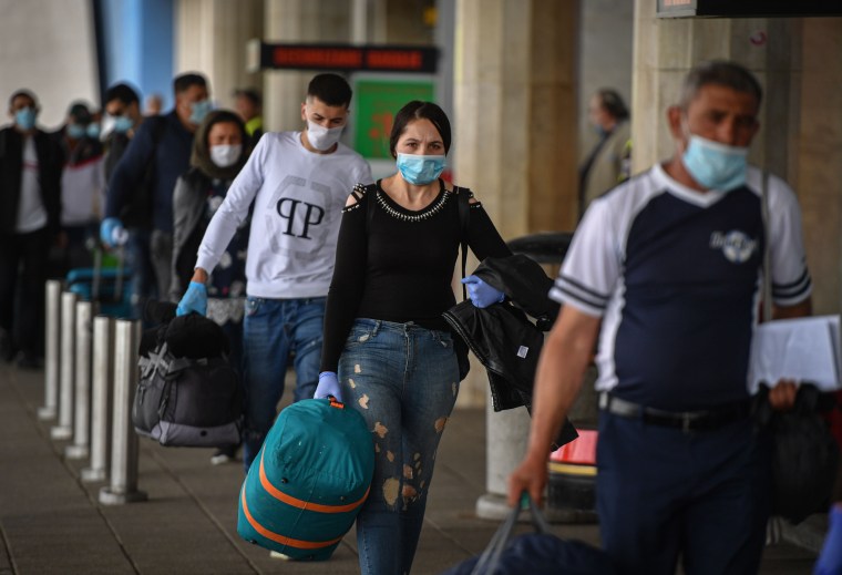 Image: Romanian harvest workers heading to the U.K. wait in line to enter the airport in Bucharest