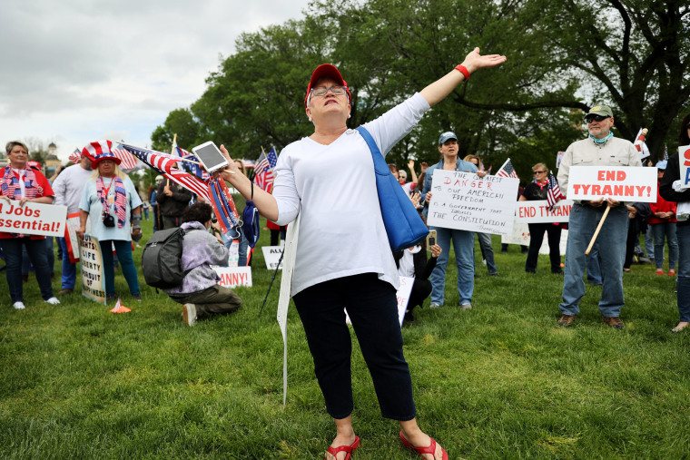 Image: A demonstrator sings  Amazing Grace during a \"Reopen Delaware\" rally calling for the reopening of the state  at the state capitol in Dover