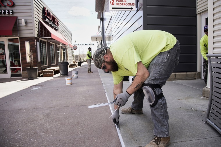 Image: Maintenance workers touch up a sidewalk