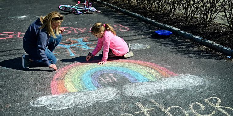 Mother and daughter draw inspirational chalk signs on sidewalk during pandemic