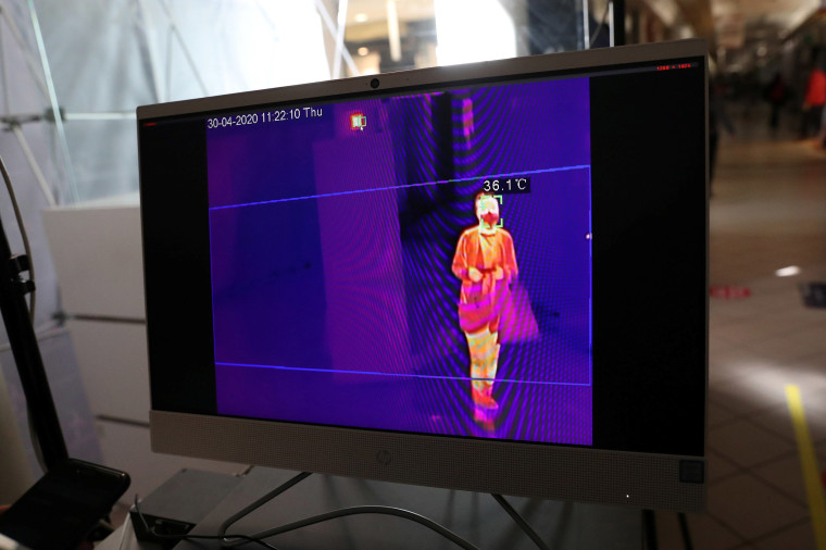 Image: A screen shows a thermal imaging system taking the corporal temperature of a customer carrying bags at the entrance to a reopened commercial center, following the coronavirus disease (COVID-19) outbreak, in Santiago, Chile