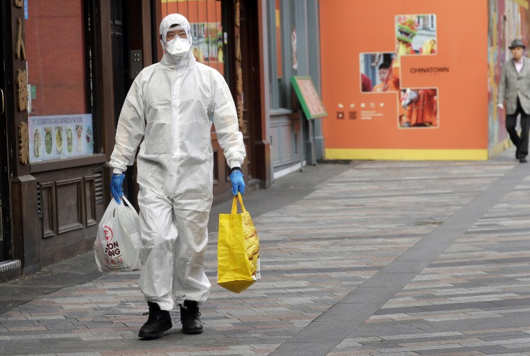 Image: A man wears full protective equipment to protect against the coronavirus as he shops in London